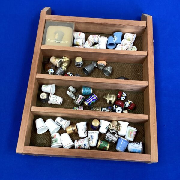 Vintage thimble collection displayed in a wooden case.