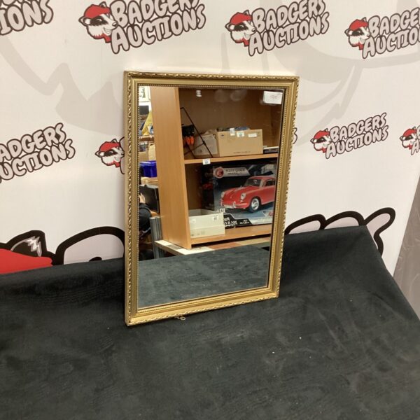 Antique gilt framed mirror with ornate detailing and a gold finish.