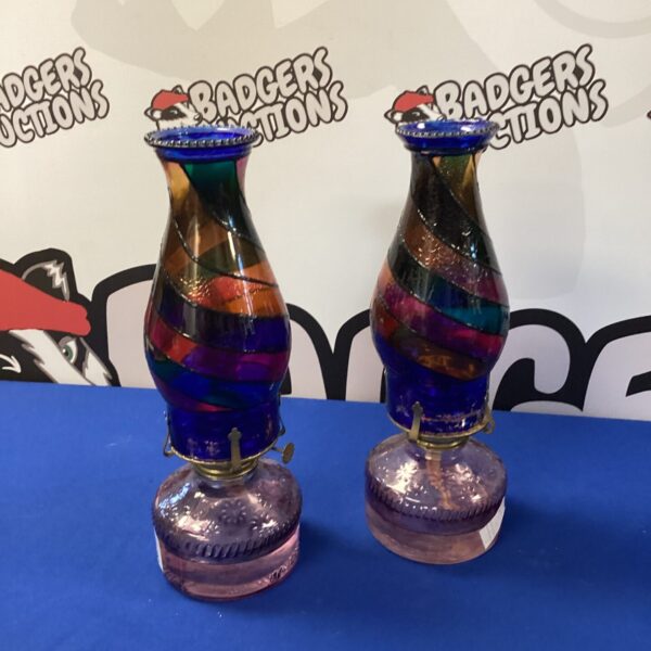 Two vintage coloured glass paraffin lamps on display.