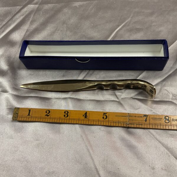 Close-up of vintage bronze paper knife with ornate handle.