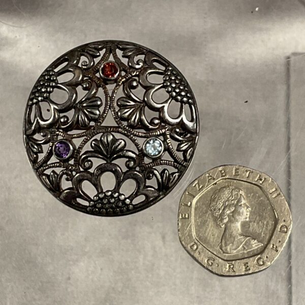 Vintage silver brooch with garnet, amethyst, and topaz gemstones.