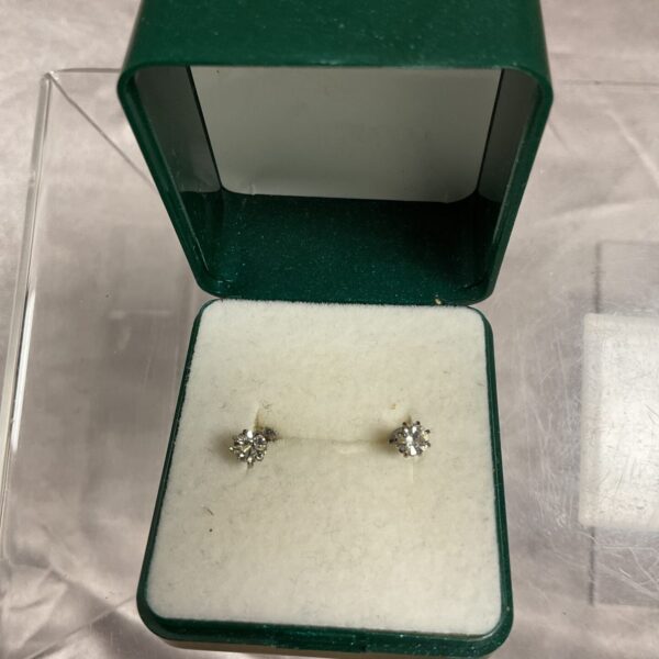 Close-up of elegant white stone stud earrings on a display cushion.