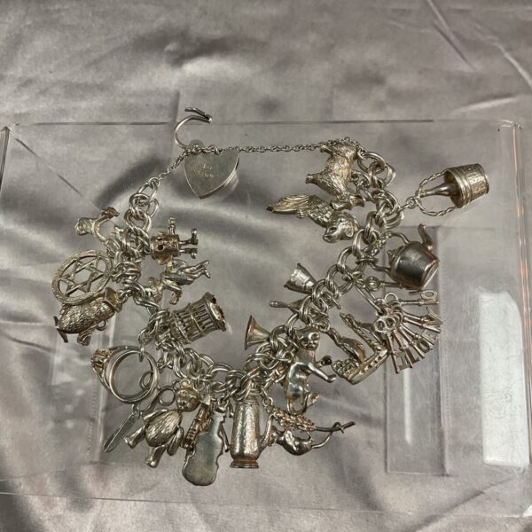 Vintage silver charm bracelet with twenty assorted charms.