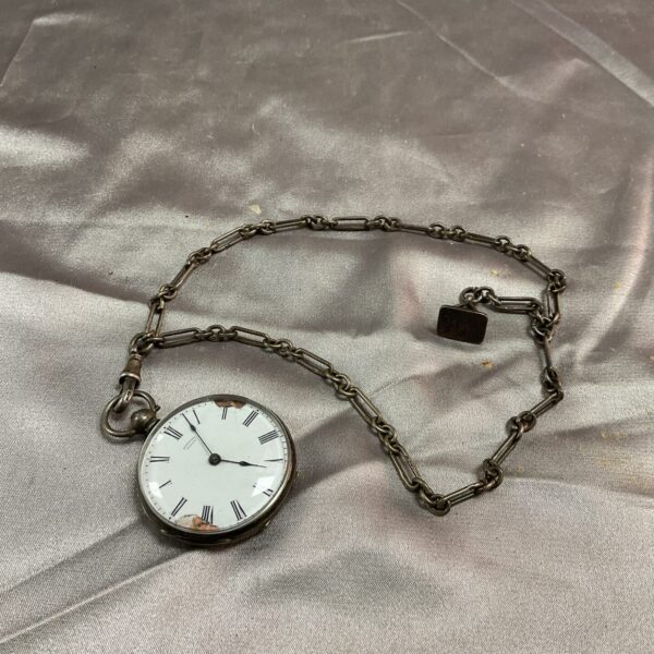 Antique silver fob chain and vintage pocket watch on display.
