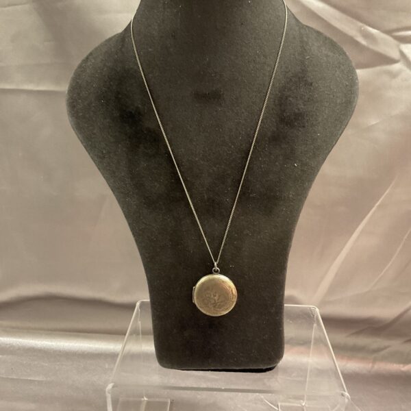 Vintage silver heart locket necklace on a chain.