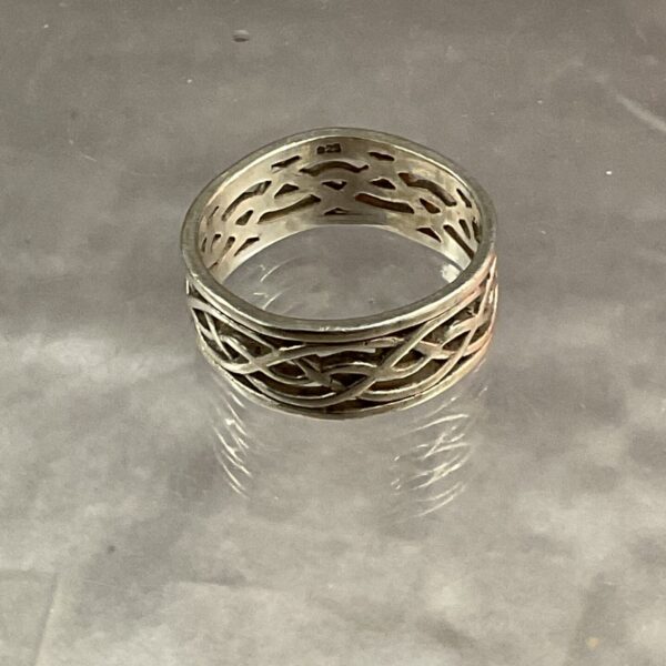 Close-up of silver Celtic ring with intricate knot pattern.