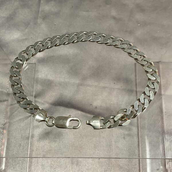 Close-up of a silver curb chain bracelet with interlocking links.