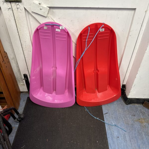 Pair of vintage plastic snow sleds for winter fun.