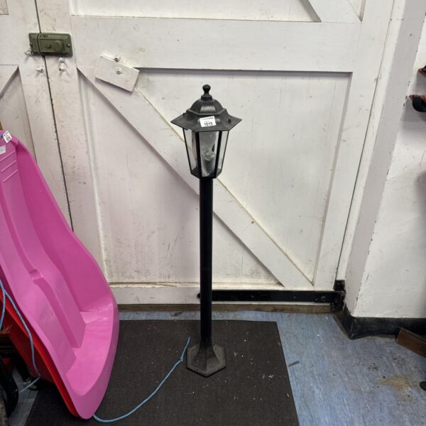 Black garden post lamp against white door.