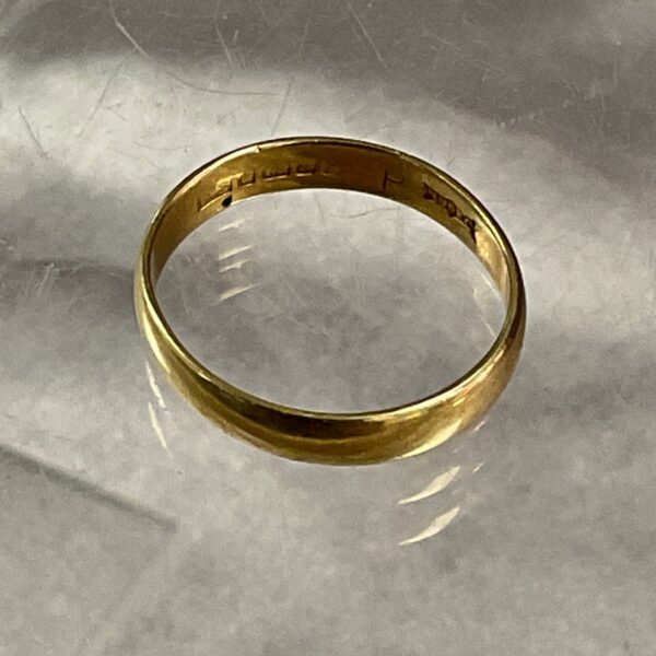 Close-up of an 18ct gold band ring, showcasing its simple design.