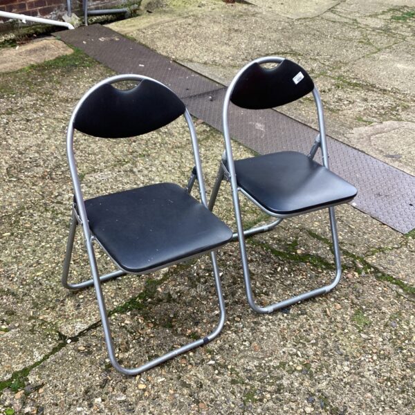 Two vintage folding padded chairs with metal frames.