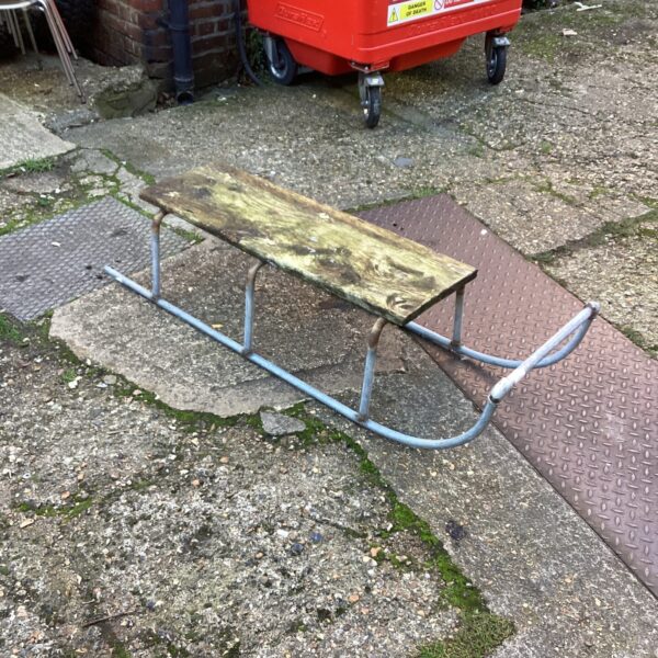 Vintage wooden sledge with metal frame, ideal for winter fun.