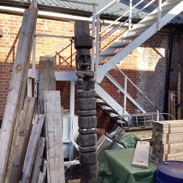 Weathered hand-carved totem pole in an outdoor setting.
