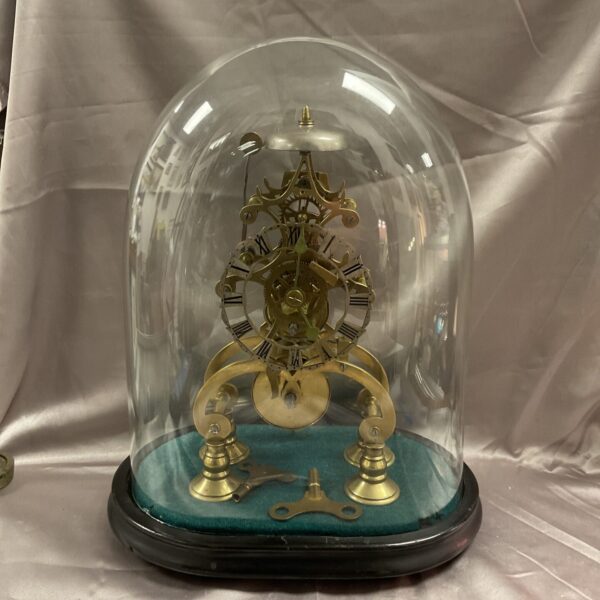 Victorian skeleton clock under glass dome, brass framework visible.