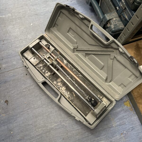 Manual tile cutter in a carrying case for DIY flooring projects.