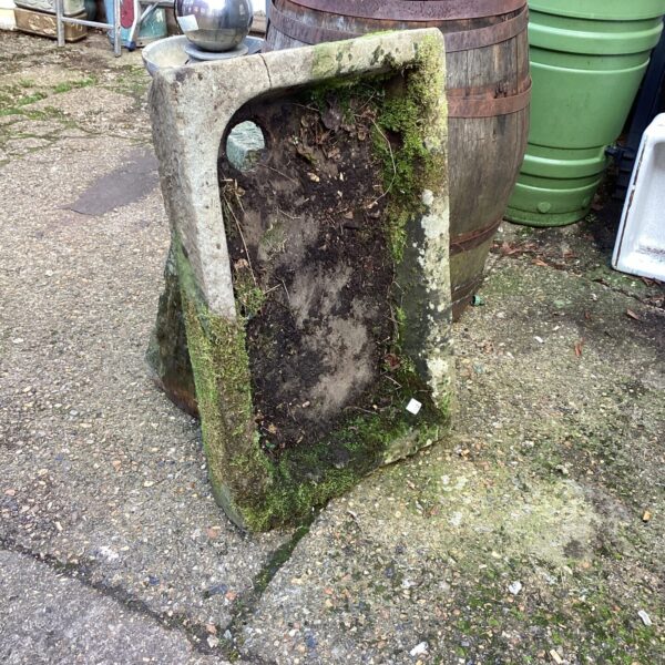 Weathered antique stone cattle trough in a garden setting.