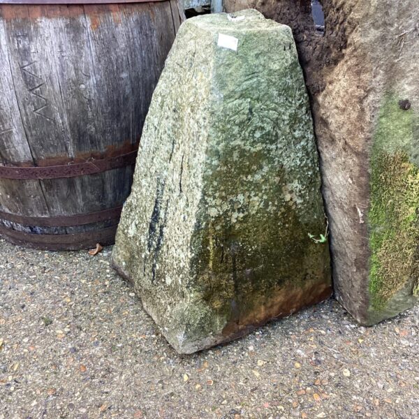 Weathered staddle stone in a garden setting, rustic architectural feature.