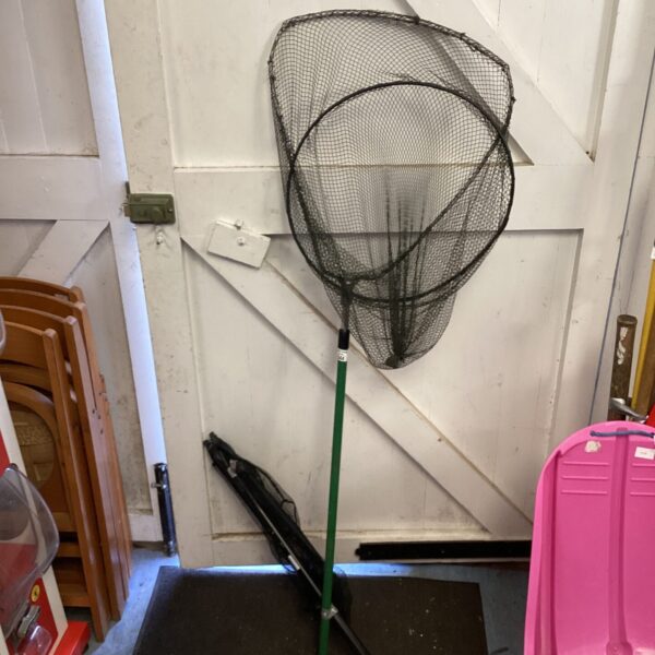 Vintage fishing landing net with green handle and dark mesh.