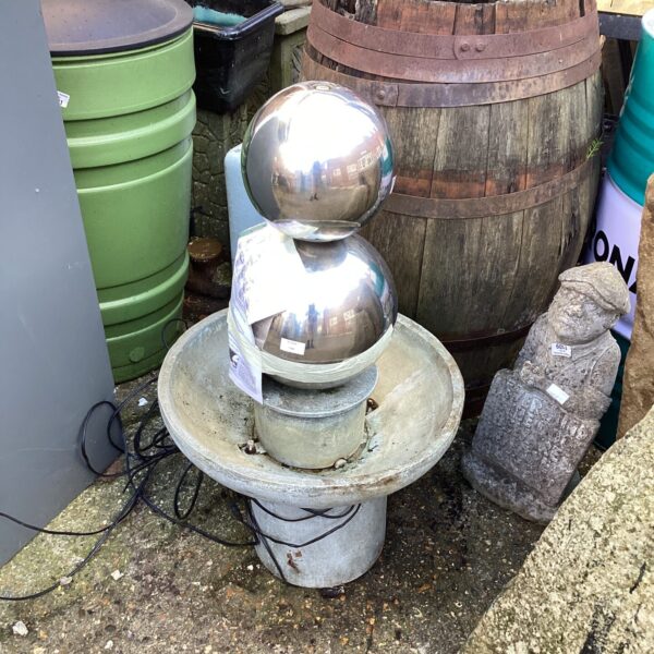 Modernist garden fountain with reflective sphere and concrete base.