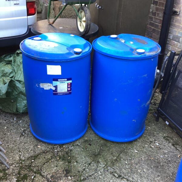 Two blue plastic drums for storage and garden use.