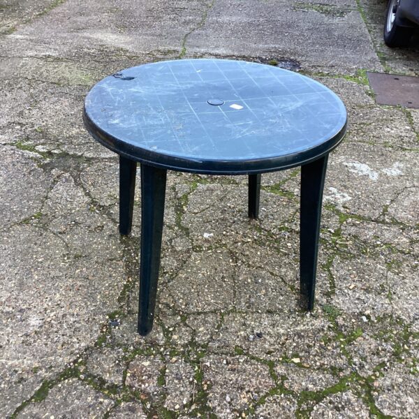 Used plastic garden table on a patio surface.