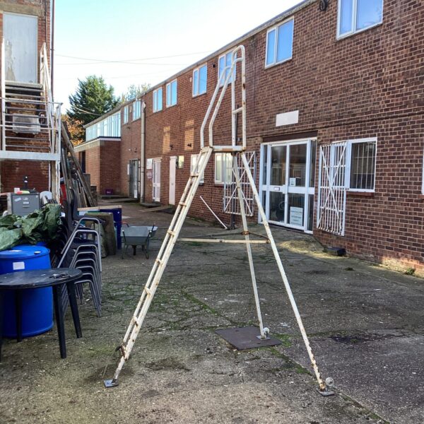 Metal Henchmans tripod ladder in an outdoor setting.