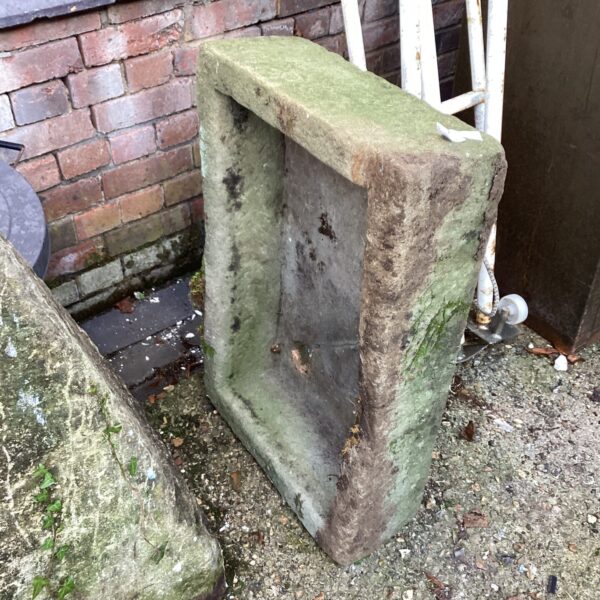 Weathered antique stone cattle trough in a garden setting.