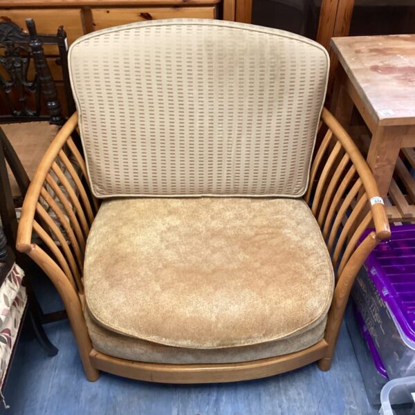 Vintage ercol cuddle chair with beech frame and faded upholstery.