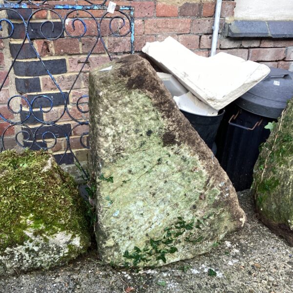 Weathered antique staddle stone in a garden setting.