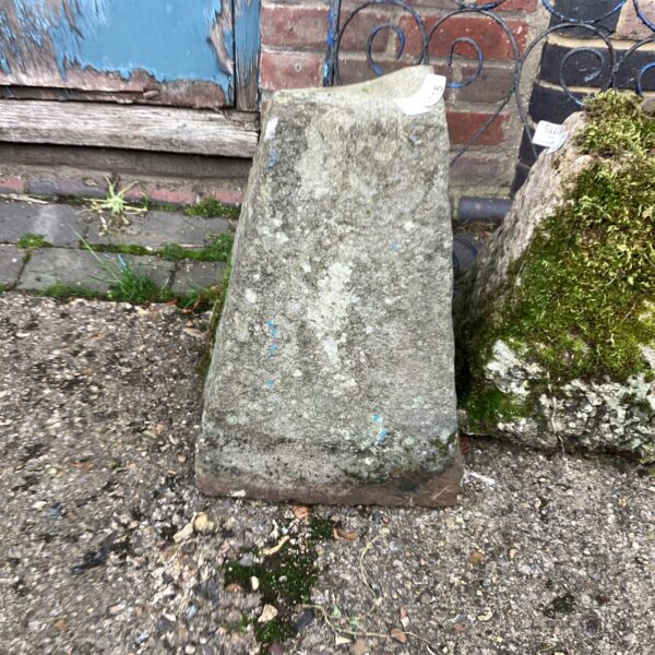Weathered antique staddle stone in a garden setting.