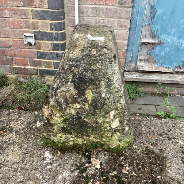 Weathered staddle stone in a garden setting, historic farmhouse feature.