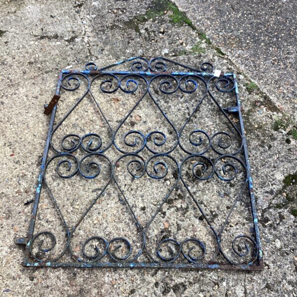 Ornate vintage metal garden gate with scrolling design.