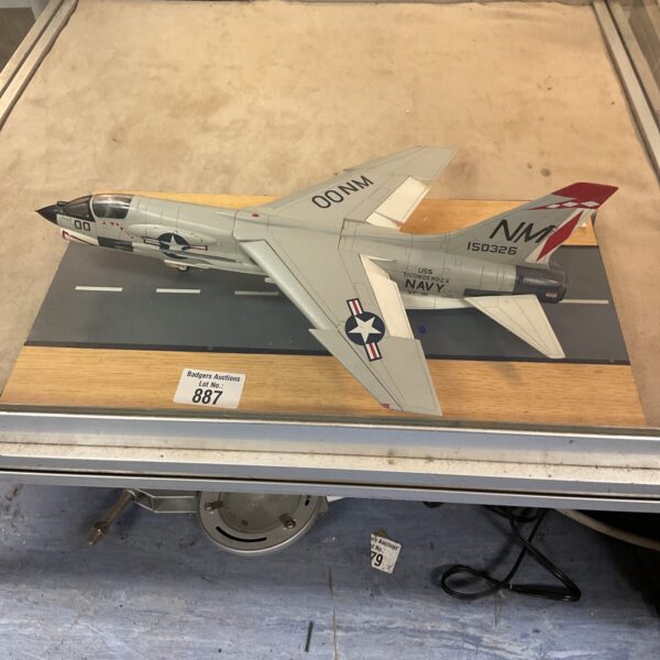 Vintage US Navy Crusader model fighter jet on display stand.