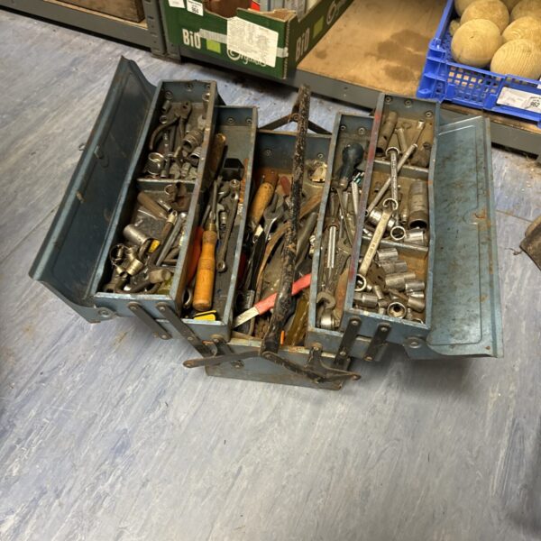 Vintage metal cantilever toolbox filled with various tools.