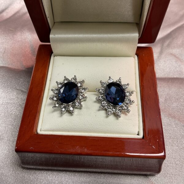 Close-up of amethyst and white stone stud earrings on a display cushion.