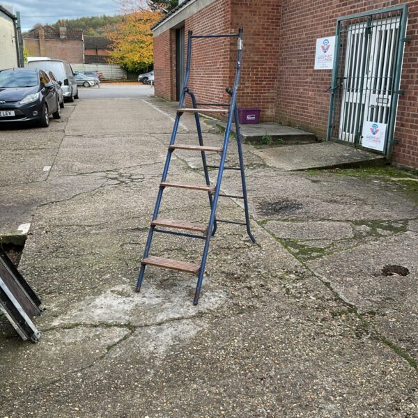 Silver aluminium decorators step ladder leaning against a brick wall.