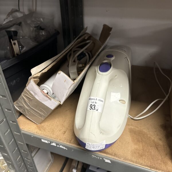 Vintage handheld electric clothes brush on a metal shelf.