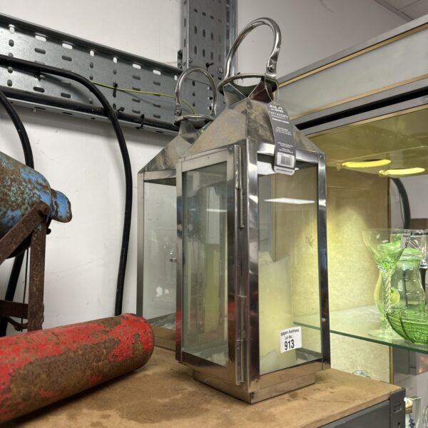 Polished metal hurricane lantern with a handle and glass panels.