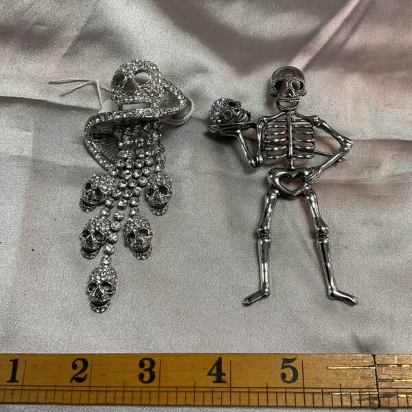 Pair of vintage skeleton brooches with white stones.