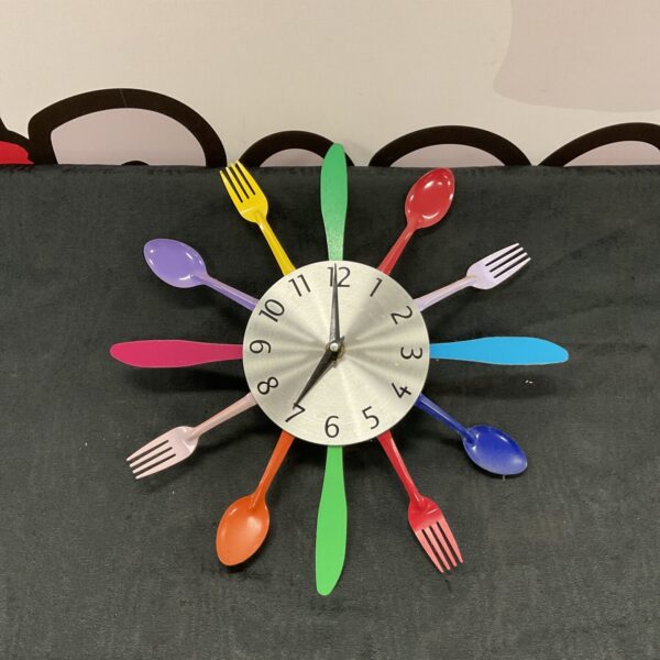 Vintage tin cutlery clock on a dark background.