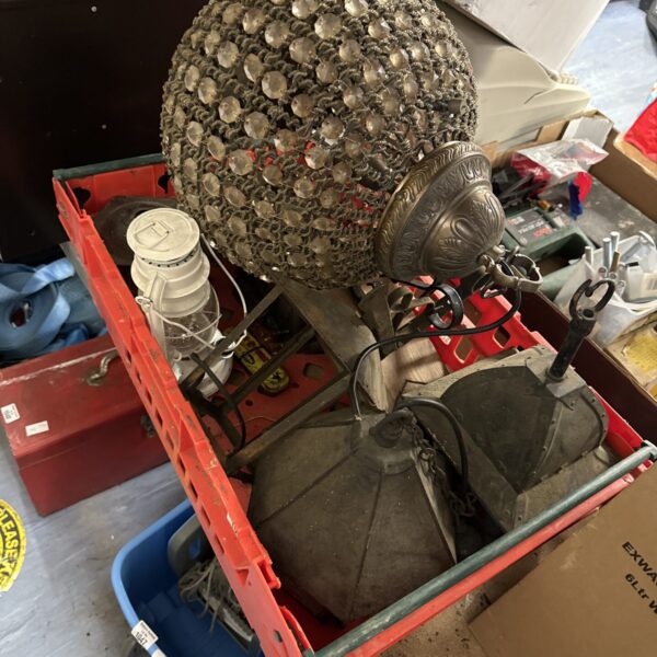 Assorted vintage lamps and lanterns in a tray, showcasing antique lighting.