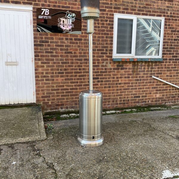Stainless steel patio heater in a garden setting.