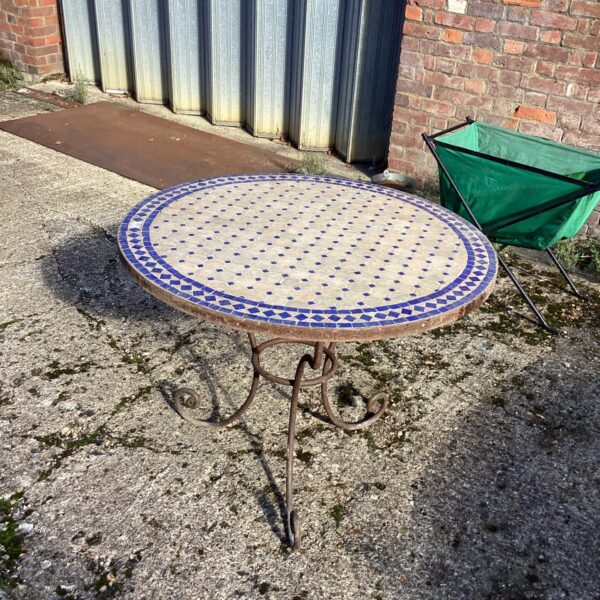 Vintage tiled garden table with mosaic design in a garden setting.