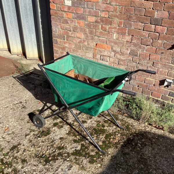 Green folding garden barrow for plant transport.