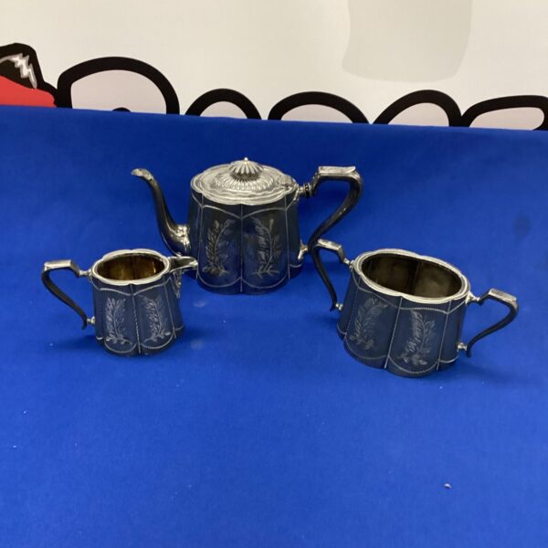 Vintage silverplated tea set with engraved floral details.