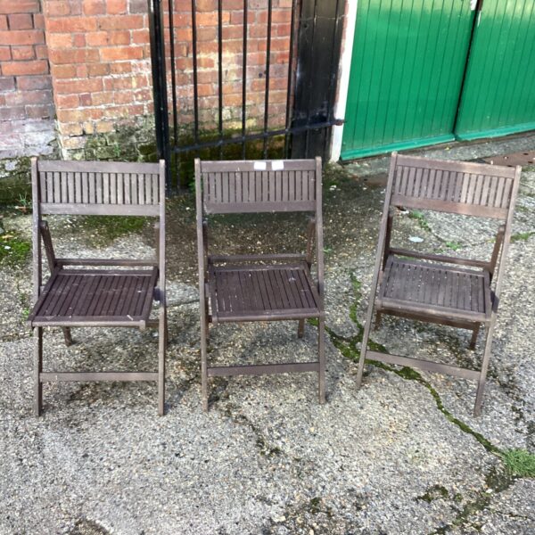Three vintage teak garden chairs in a garden setting.