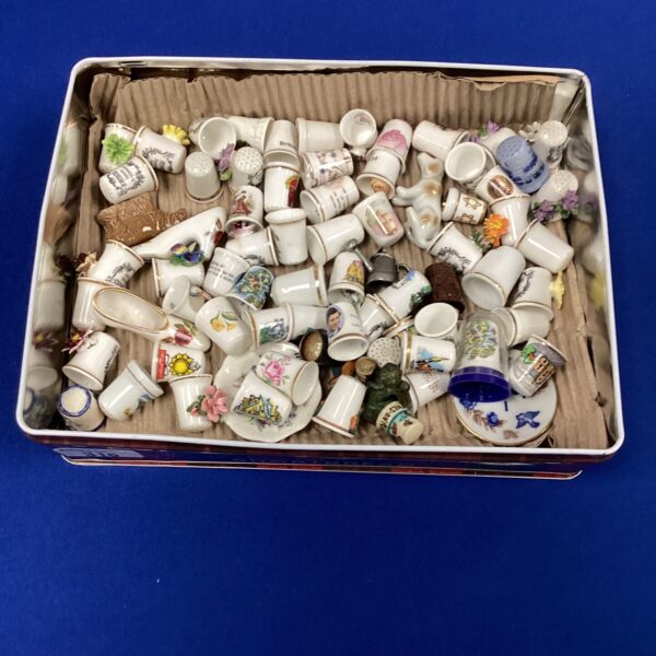 Vintage porcelain thimble collection displayed in a box.