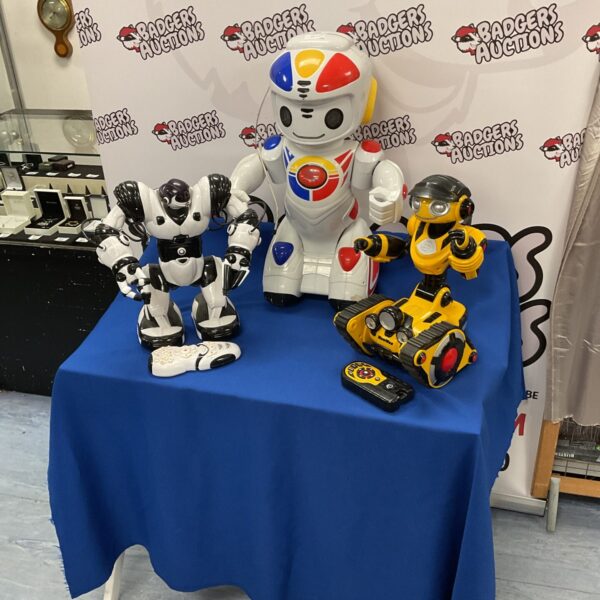 Three vintage interactive robots with controls displayed on a table.