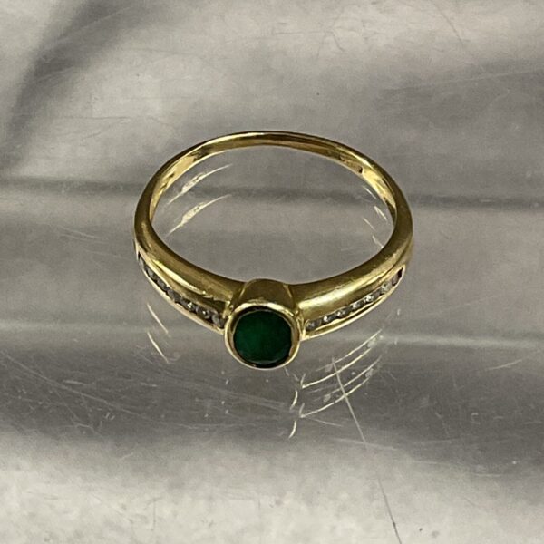 Close-up of a 9ct gold ring with emerald and diamond accents.