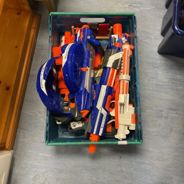 Crate of mixed Nerf blasters and foam dart toy guns.